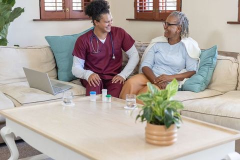 Home healthcare nurse visiting senior african american woman sharing warm conversation