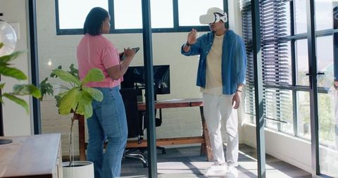 Team Collaborating in Glass Office with VR Headset and Tablet for Immersive Product Testing