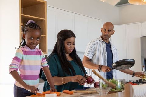 African american family cooking together at modern kitchen island preparing vegetables
