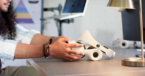 Mid-adult man handling white vr headset in modern tech workspace for hardware prototype