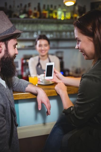 Woman showing mobile phone to man in cafÃ©