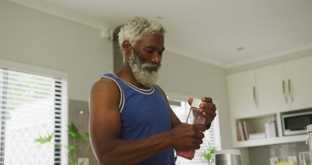 Image of happy african american senior man preparing smoothie. retirement lifestyle, spending time alone at home concept digitally generated image.