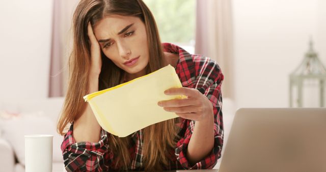 Upset brunette with calculator paying bills at home