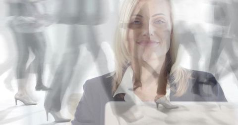 Smiling businesswoman working at laptop while commuters move past in double exposure