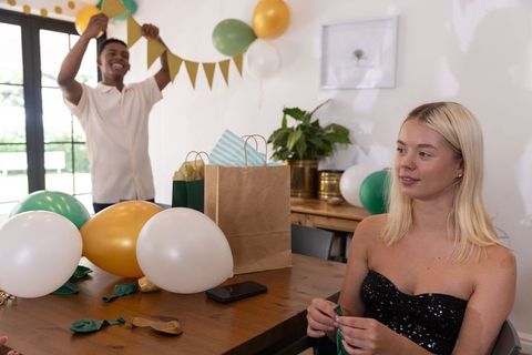 Friends decorating room with balloons and banners for celebration