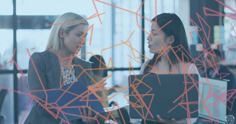 Discussing project with blue folder and laptop in open-plan office with orange decals