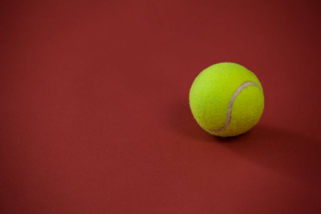 High angle view of tennis ball against maroon background