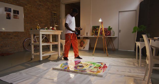 African american male artist pouring paint on canvas at art studio. art, hobby and creative occupation concept