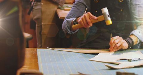 Craftsman Carefully Working with Leather Tools in Workshop