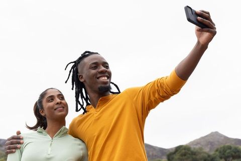 Couple taking selfie on foothills in activewear smiling during outdoor hike