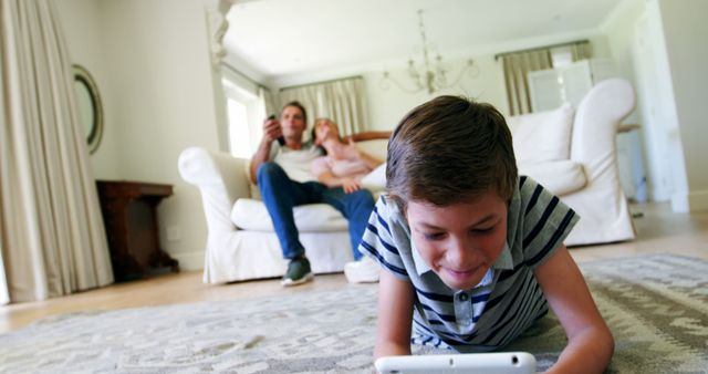 Boy Playing Video Game on Tablet with Parents Relaxing on Couch in Background - Download Free Stock Photos Pikwizard.com