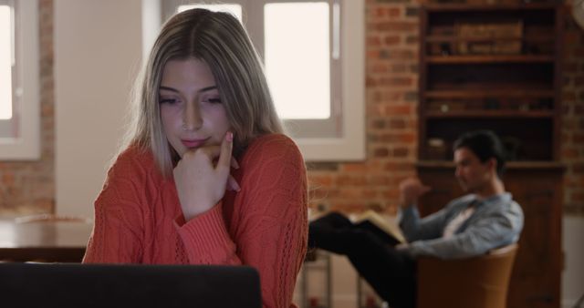 Young Woman Studying on Laptop at Home with Friend in Background - Download Free Stock Images Pikwizard.com