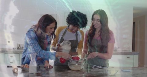 Three friends mixing batter on kitchen island wearing aprons laughing and baking