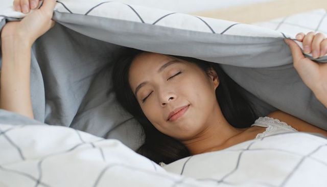 Serene woman sleeping under geometric duvet while holding blanket for cozy morning rest