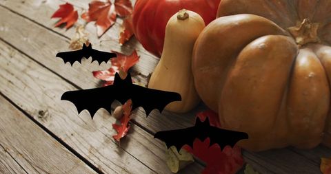 Pumpkins and Autumn Leaves with Flying Bats on Wooden Background