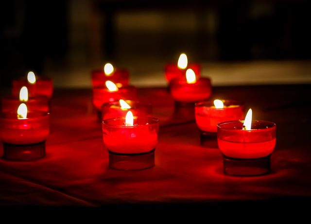 Red candlelights glowing in small glass holders creating a serene atmosphere. Ideal for illustrating themes of relaxation and meditation. Can be used on websites, blogs, and magazine articles focusing on calming environments, spirituality, or romantic settings.