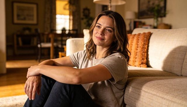 Woman relaxing on living room floor leaning against sofa in warm golden light