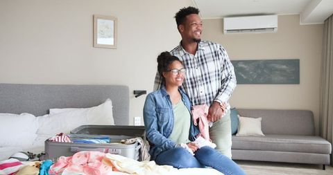 Couple Smiling While Unpacking Suitcase in Hotel Room