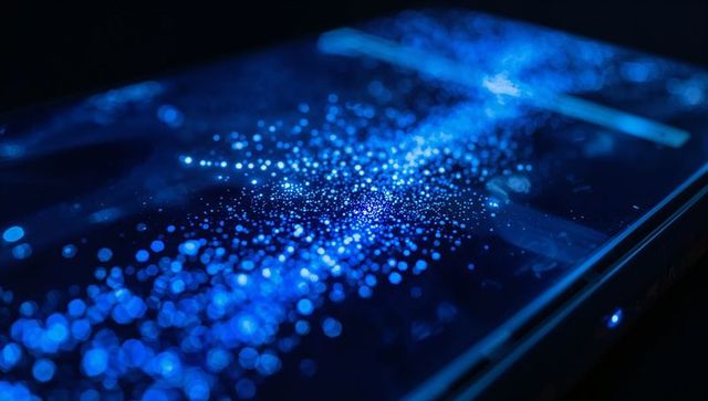 Smartphone screen emitting blue bokeh particles with cyan glow and led bezel macro