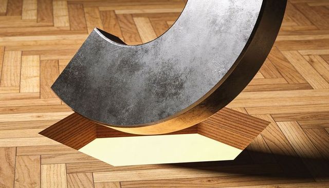 Large weathered metal arc resting on parquet floor with glowing pentagon inlay