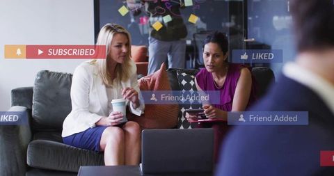 Business women collaborating with modern technology in lounge area
