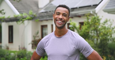 Smiling man in eco-friendly home yard with solar panels