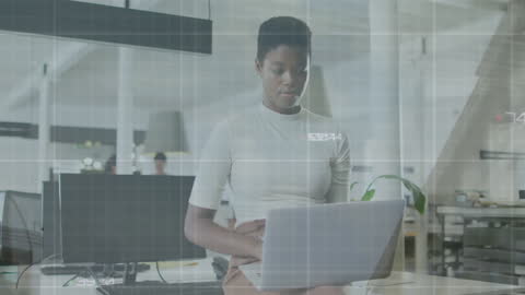African American Woman Using Laptop with Data Overlay in Modern Office