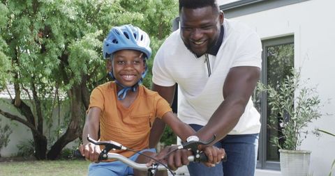 Father Supports Son Learning to Ride Bike Outdoors