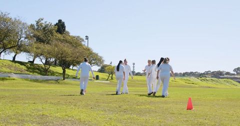 Female Athletes Practicing Teamwork on Sunny Turf Near Canal