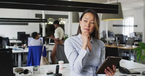Focused Asian Businesswoman using Tablet in Modern Office