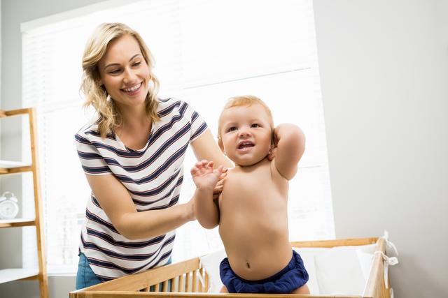 Mother playing with her baby boy in a bright nursery. Ideal for parenting blogs, family lifestyle articles, and advertisements for baby products. Showcases the joy and bond between mother and child.