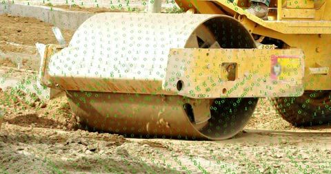 Steel roller compacting soil with yellow chassis and green binary overlay