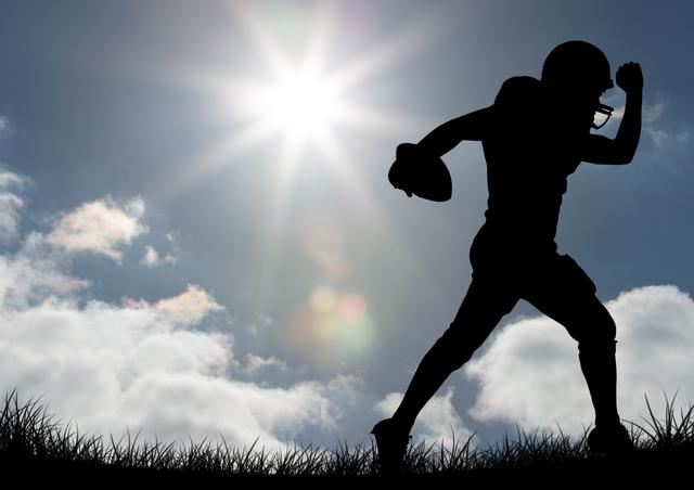 Silhouette of rugby player running with ball, backlit by the bright sun, creating a dramatic effect. Grass blades capture the essence of the field, evoking feelings of motion and athleticism. Ideal for sports promotions, motivational materials, fitness and training content, and advertisements focusing on outdoor activities.
