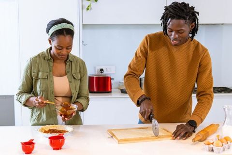 African american couple preparing pastry together on modern kitchen island