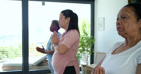 Pregnant woman meditating with african american senior women prenatal mindfulness at home
