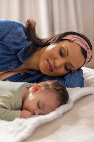 Caregiver bonding with sleeping infant on plush blanket in cozy bedroom