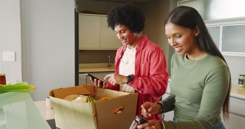 Friends Unpacking Groceries and Discussing Meal Plans in Modern Kitchen