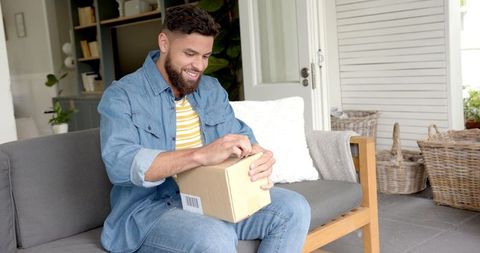 Man Relaxing on Patio Opening Parcel with Excitement