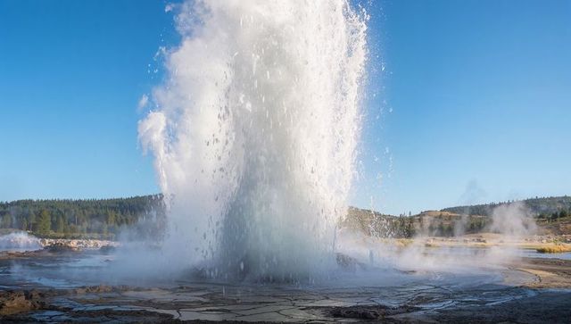 Erupting geyser sending towering water and steam plume over mineral crusted geothermal basin