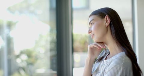 Thoughtful Young Woman with Long Hair Looking Out Window