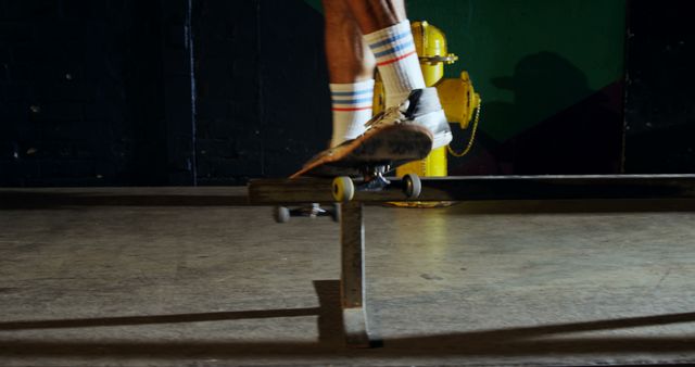Skateboarder is performing a grind trick on a metal rail in an indoor skate park. Only the feet, shoes, skateboard, and the rail are visible. This can be used for promoting active lifestyles, skateboarding events, or sports equipment. It emphasizes movement, skill, and the urban, active nature of skateboarding.