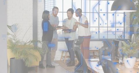 Diverse team collaborating and reviewing files on tablet and laptop in coworking office