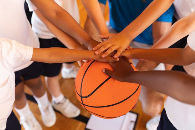 Close-up of Schoolkids forming hand stack on basketball at basketball court - Download Free Stock Photos Pikwizard.com