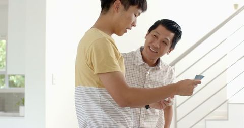 Man Engaging with Son at Home Reading Letter Together