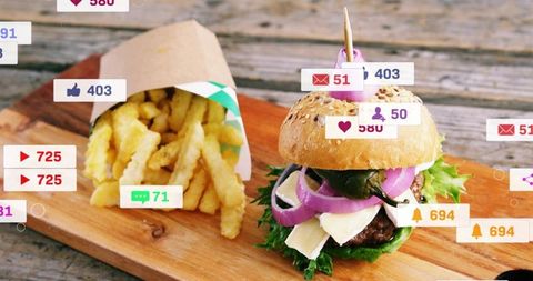 Gourmet sesame bun burger skewering with pick, crinkle fries on rustic wooden board, social overlays