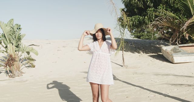 Happy hispanic woman in sunhat and sundress smiling on sunny beach, slow motion. Summer, relaxation and vacations.