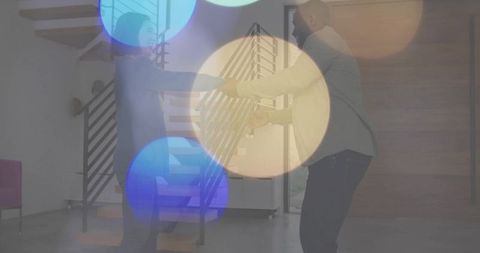 Holding hands couple by floating staircase in modern minimalist entryway, intimate connection