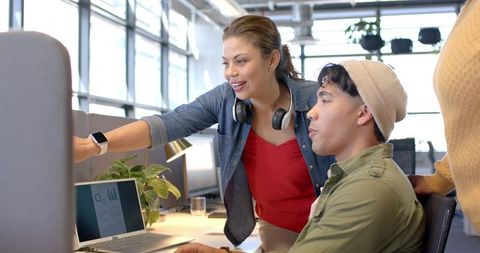 Open-Plan Team Collaborating at Workstation Woman Pointing at Monitor Reviewing Data