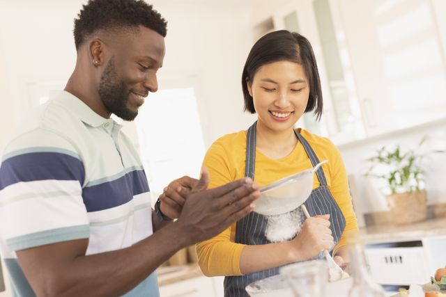 Happy diverse couple baking together in kitchen. Spending quality time at home, domestic life and lifestyle concept.