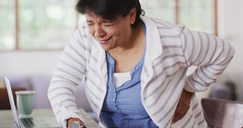 Elderly woman experiencing lower back pain at home